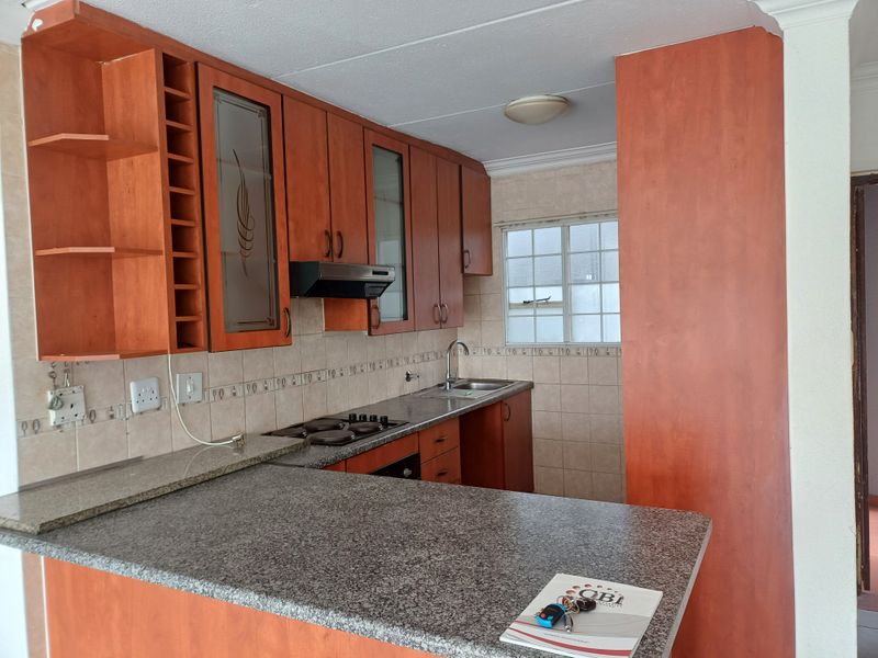 A functional kitchen featuring wood-finish cabinetry, granite countertops, a built-in hob and oven, and a convenient breakfast bar for casual dining.