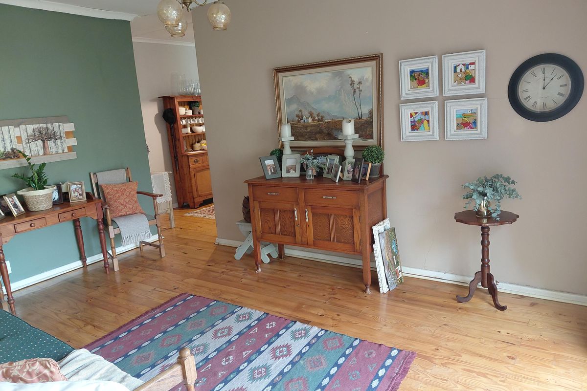 A living room featuring polished hardwood flooring and a neutral color palette with an accent wall.