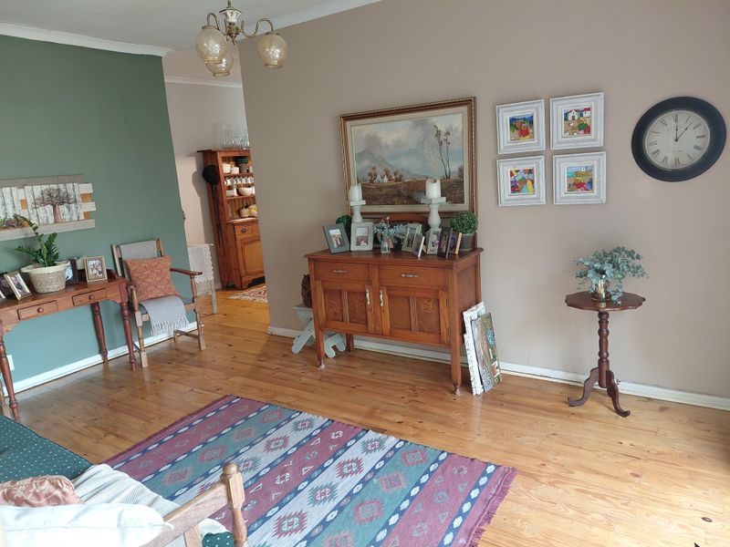 A living room featuring polished hardwood flooring and a neutral color palette with an accent wall.