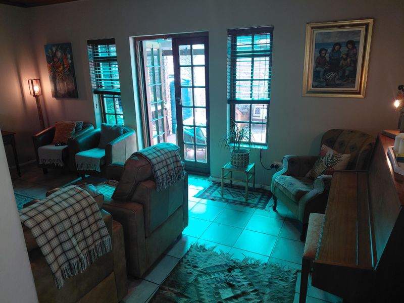 A cozy living room featuring tiled flooring and direct access to the outdoor area through classic french doors with fitted venetian blinds.