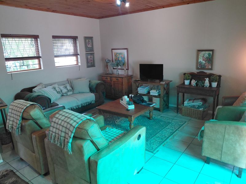 A cozy living room featuring a warm timber ceiling, tiled flooring, and natural light through venetian blinds.