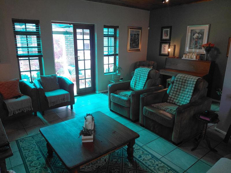 A cozy living room featuring tiled flooring, timber ceiling accents, and direct access to an outdoor patio through glass-paned french doors.