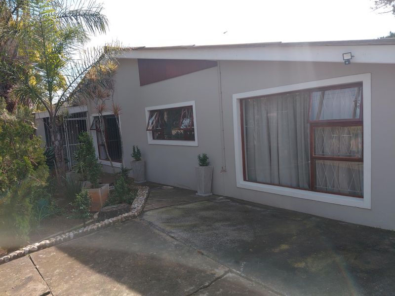 Front elevation of the house featuring a concrete driveway, security-fitted windows, and established garden beds.