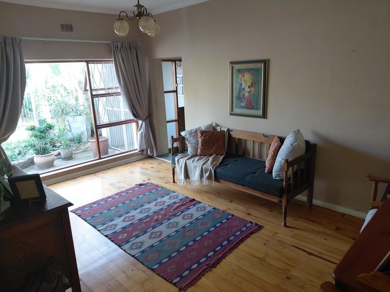 A living room featuring polished timber flooring, a large window providing natural light, and direct access to an outdoor area.