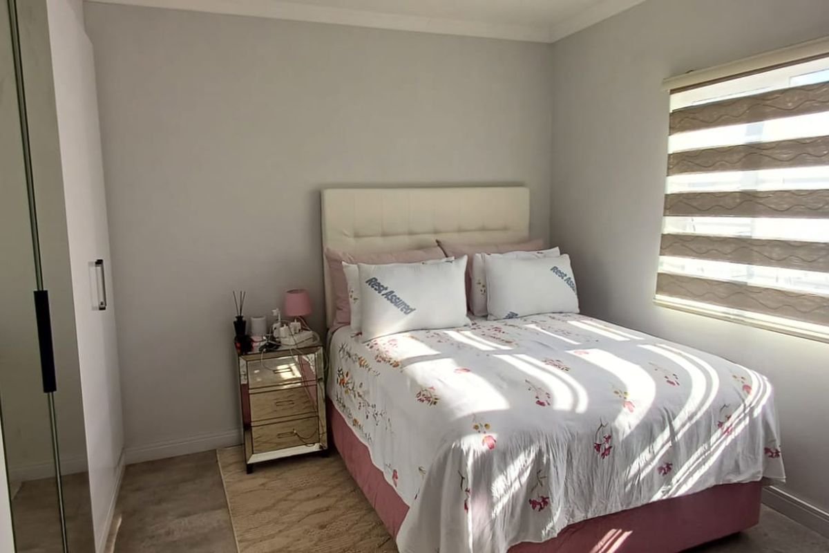 A well-maintained bedroom featuring built-in cupboards and modern roller blinds, offering a clean and functional living space.