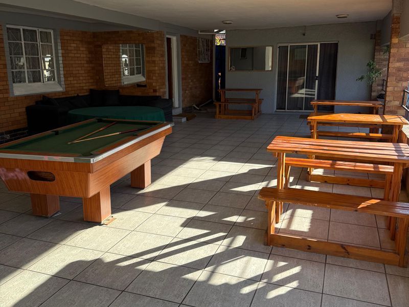 A spacious covered patio area featuring tiled flooring, exposed brick accents, and direct access to the interior through sliding glass doors.