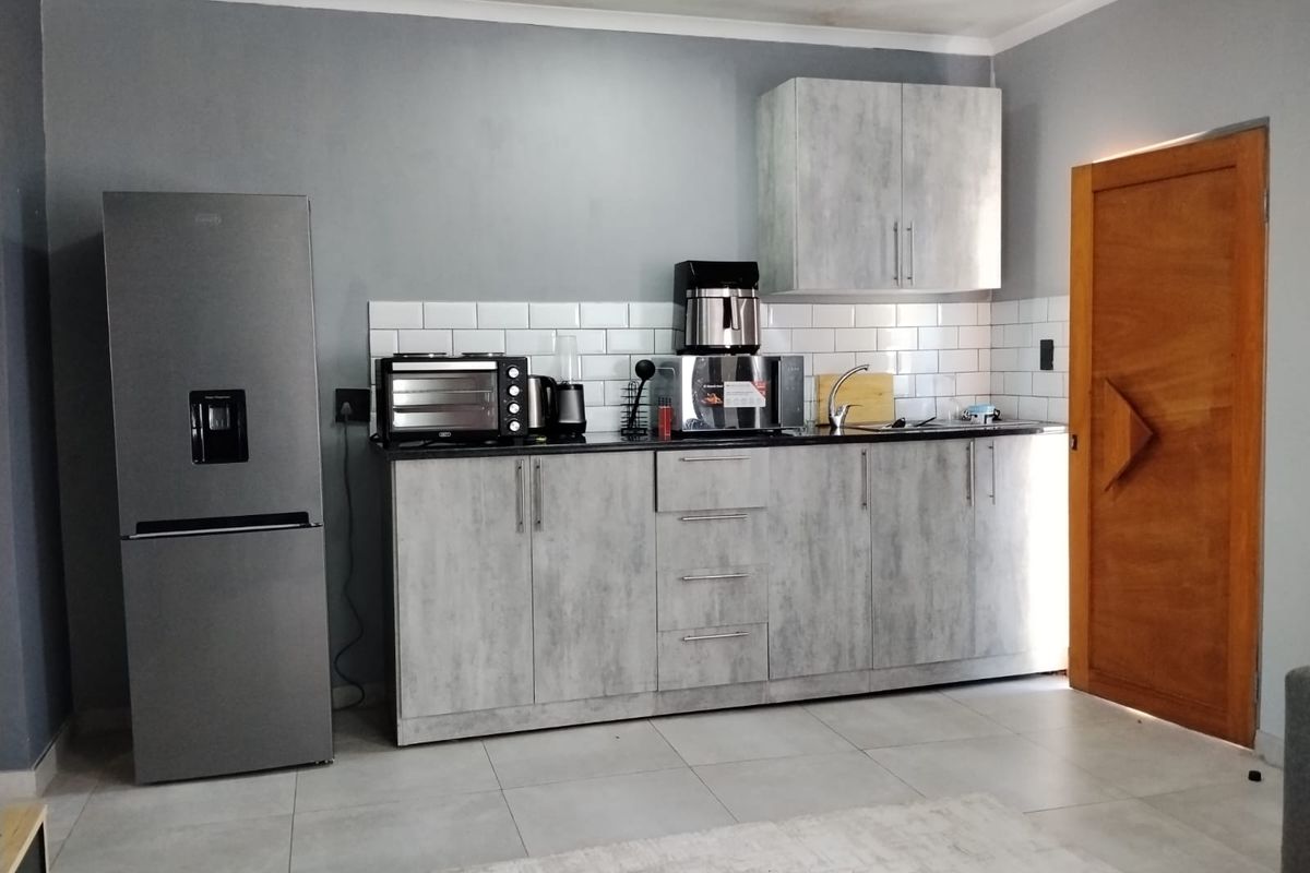 Compact kitchen featuring modern grey cabinetry, subway tile backsplash, and a stainless steel sink, providing a functional and contemporary cooking space.