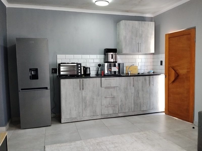 Compact kitchen featuring modern grey cabinetry, subway tile backsplash, and a stainless steel sink, providing a functional and contemporary cooking space.