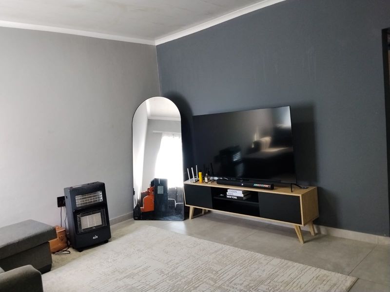 A living room featuring tiled flooring and a dark grey accent wall, providing a neutral base for interior design.