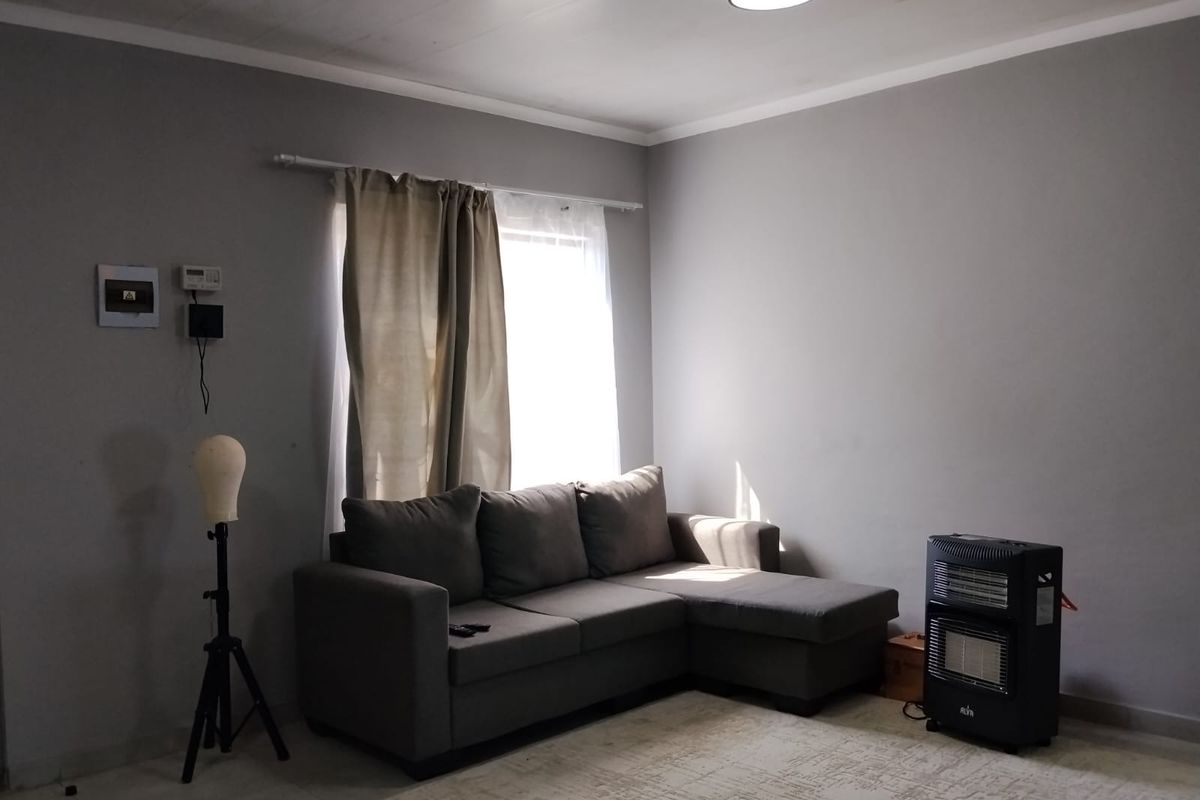 A living room featuring grey walls, a ceiling light fixture, and a window with curtain rod, providing a neutral base for interior design.