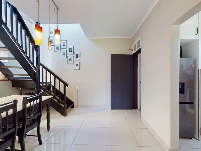 Open plan living area featuring a modern staircase, tiled flooring, and a view into the adjacent kitchen space.