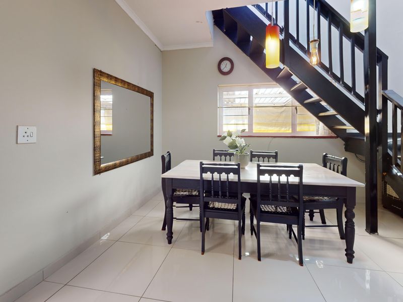 Dining area featuring tiled flooring and a staircase with a dark wooden balustrade, providing a functional space for meals.