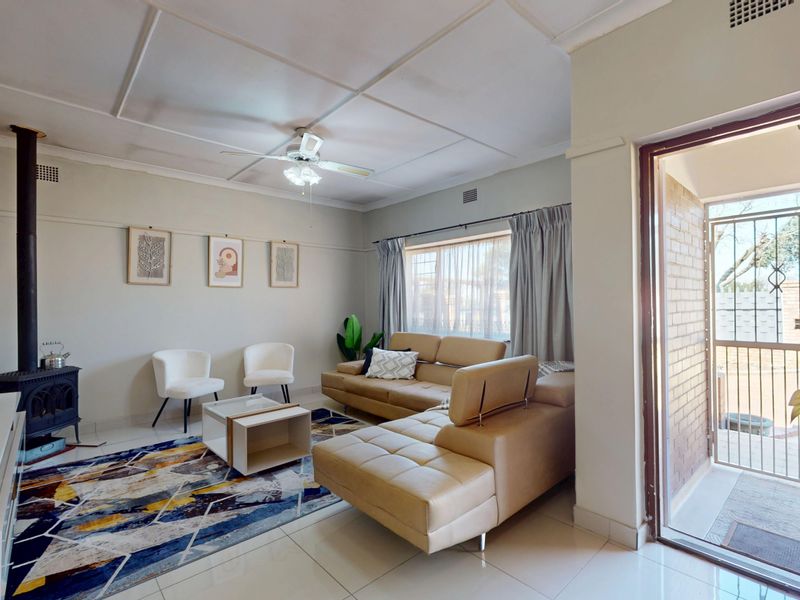 A bright living room featuring tiled floors, a freestanding fireplace, and direct access to an outdoor area through a sliding door with a security gate.