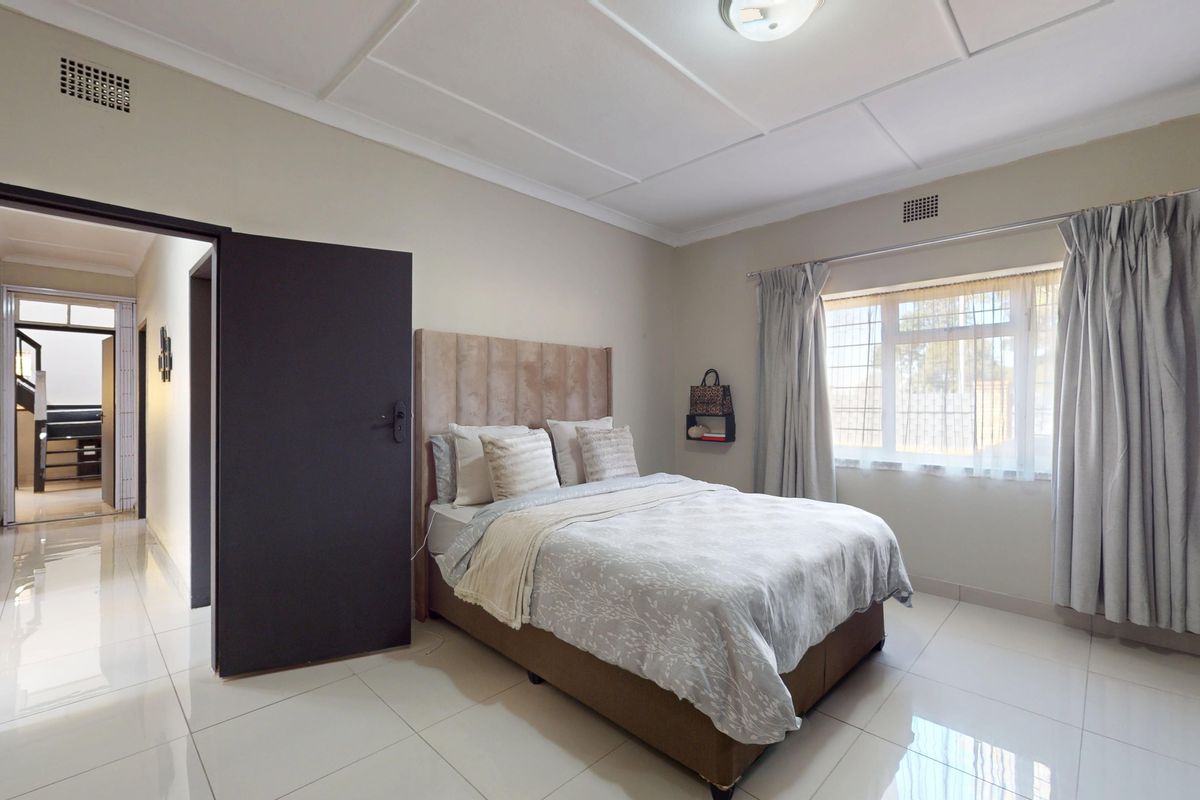 A well-maintained bedroom featuring tiled flooring, a built-in cupboard, and a window with security bars, offering a clean and functional living space.