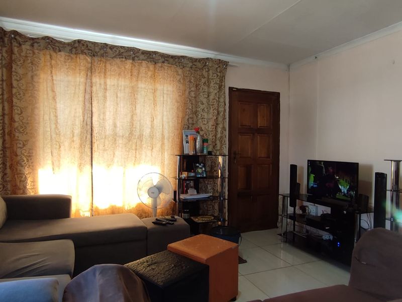 A comfortable living room featuring tiled flooring and a solid wooden door, providing a functional and inviting space for relaxation.