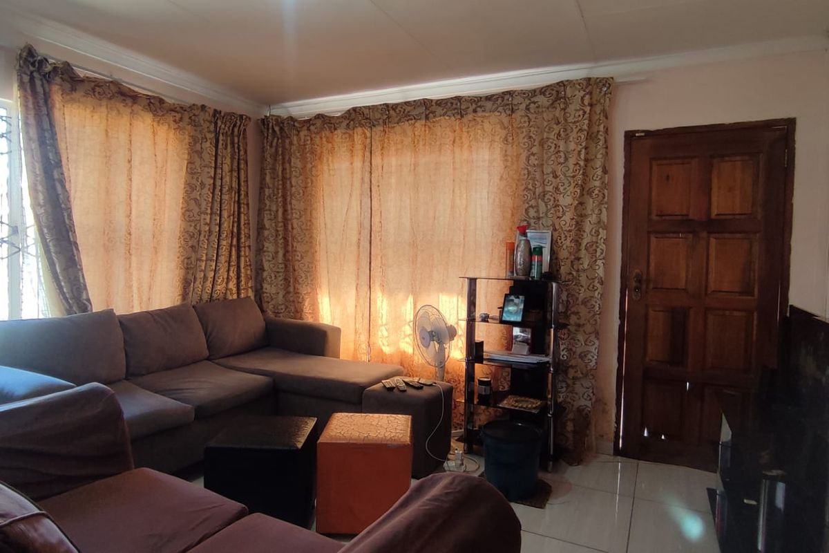 A living room featuring tiled flooring and a solid wooden door, providing a functional and comfortable space for relaxation.
