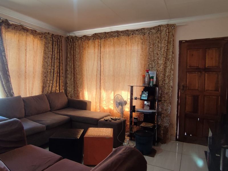 A living room featuring tiled flooring and a solid wooden door, providing a functional and comfortable space for relaxation.
