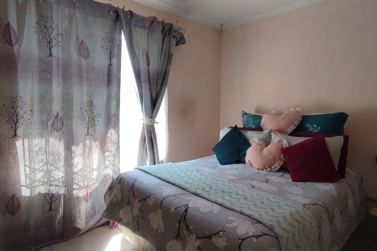 A standard bedroom featuring a window with curtains and neutral wall finishes.