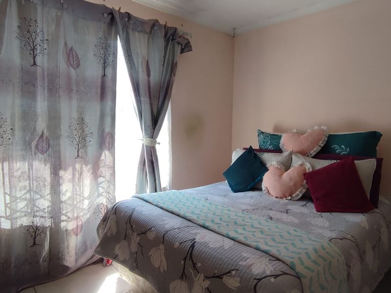A standard bedroom featuring a window with curtains and neutral wall finishes.