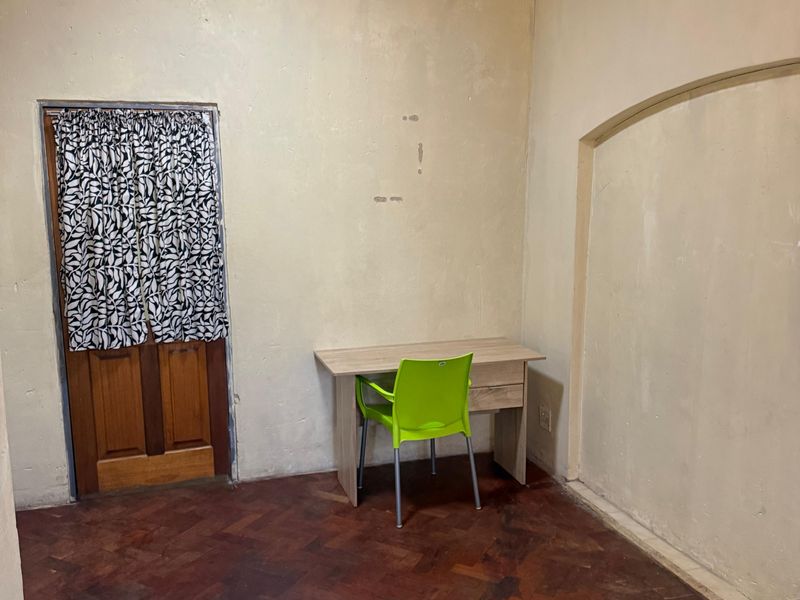 A bedroom featuring parquet flooring, a coved ceiling, and an arched wall niche, currently requiring cosmetic wall repairs and fresh paint.