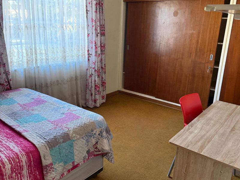 A bedroom featuring built-in wooden cupboards and carpeted flooring, offering a functional space with potential for modernization.