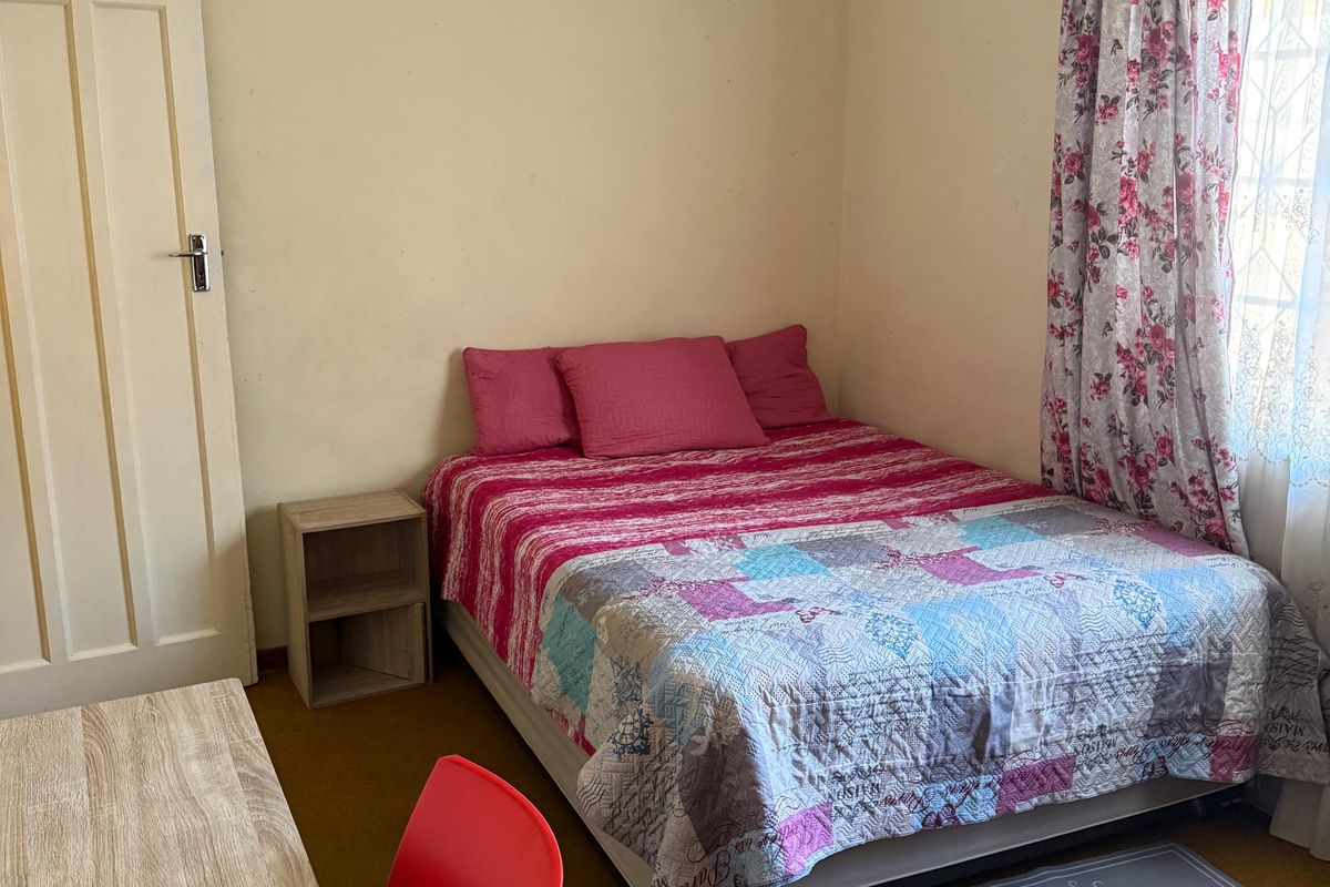 A compact bedroom featuring neutral wall finishes, a panel door, and carpeted flooring, offering a functional space ready for cosmetic updates.