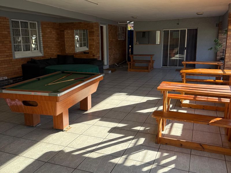A spacious covered patio area featuring tiled flooring, exposed brick walls, and direct access to the interior through sliding glass doors.