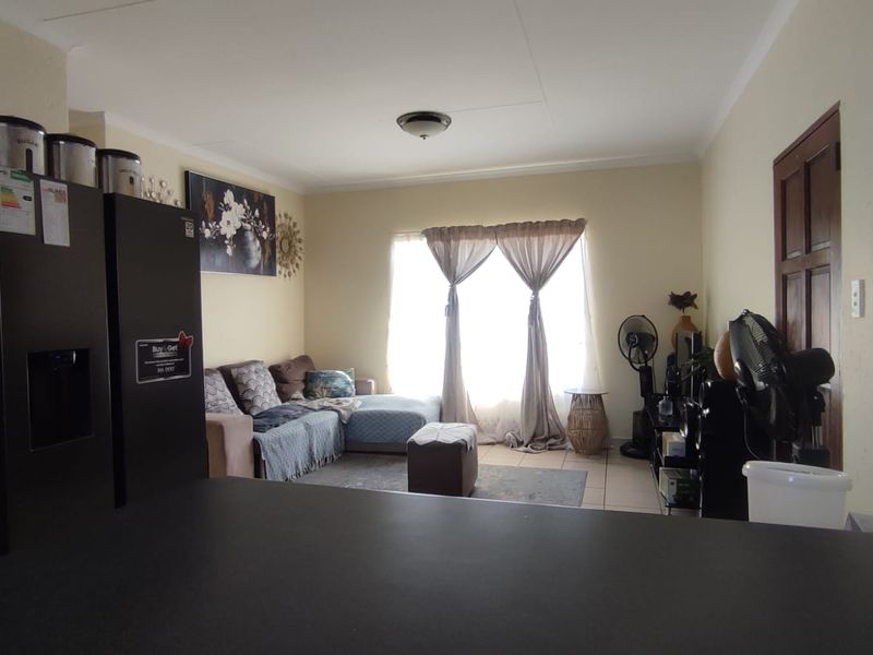 Open plan living area featuring tiled flooring, coved ceilings, and access to a patio through a sliding door.