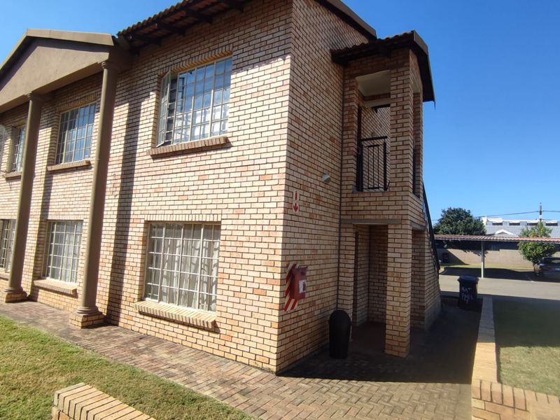 Exterior view of a multi-story apartment building featuring face brick construction, tiled roofing, and paved walkways.