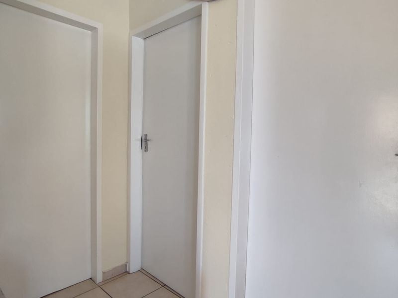 A simple hallway featuring tiled flooring and multiple internal doors with standard hardware.
