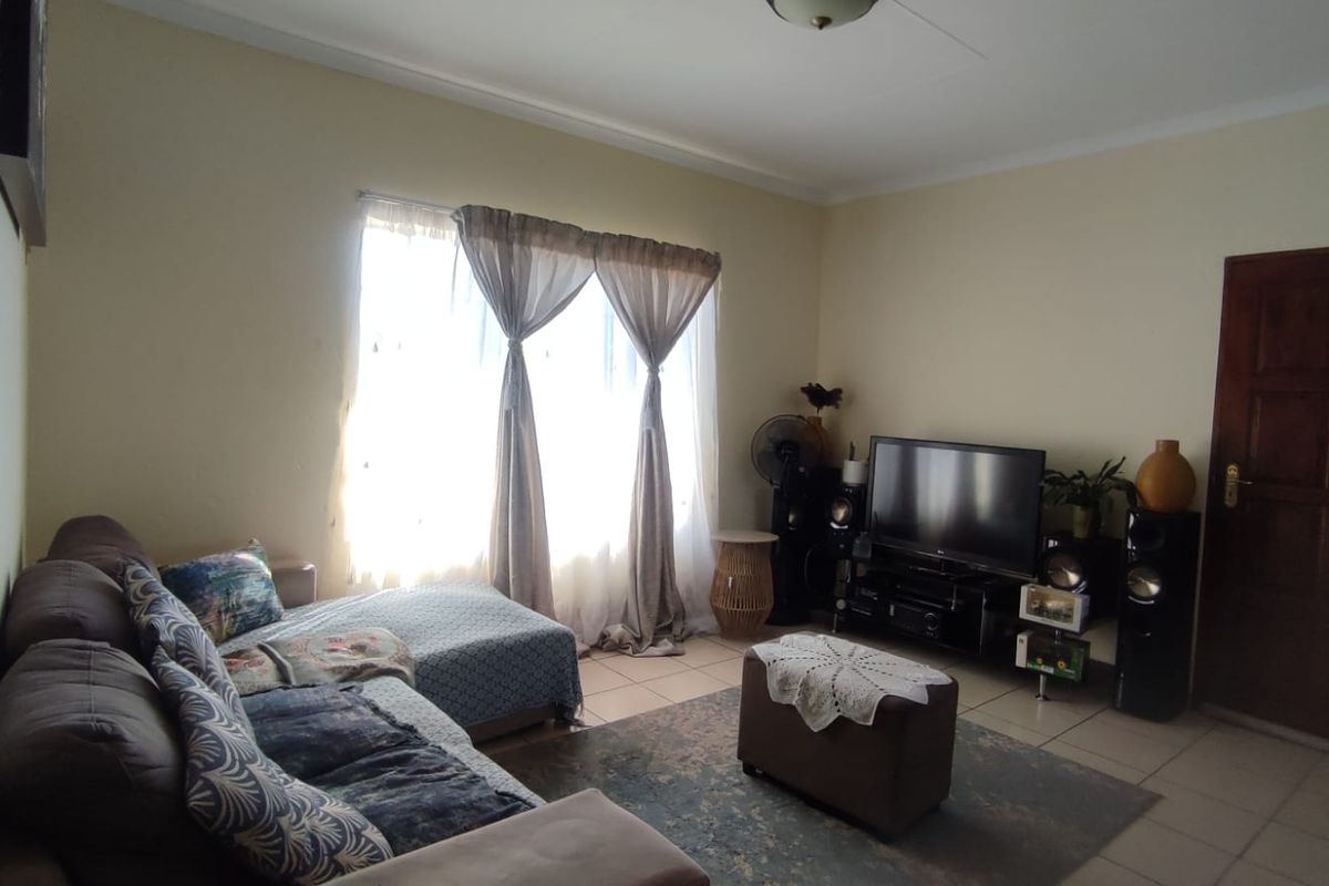 A living room featuring tiled flooring, a ceiling fan, and a wooden door, providing a functional and comfortable space.