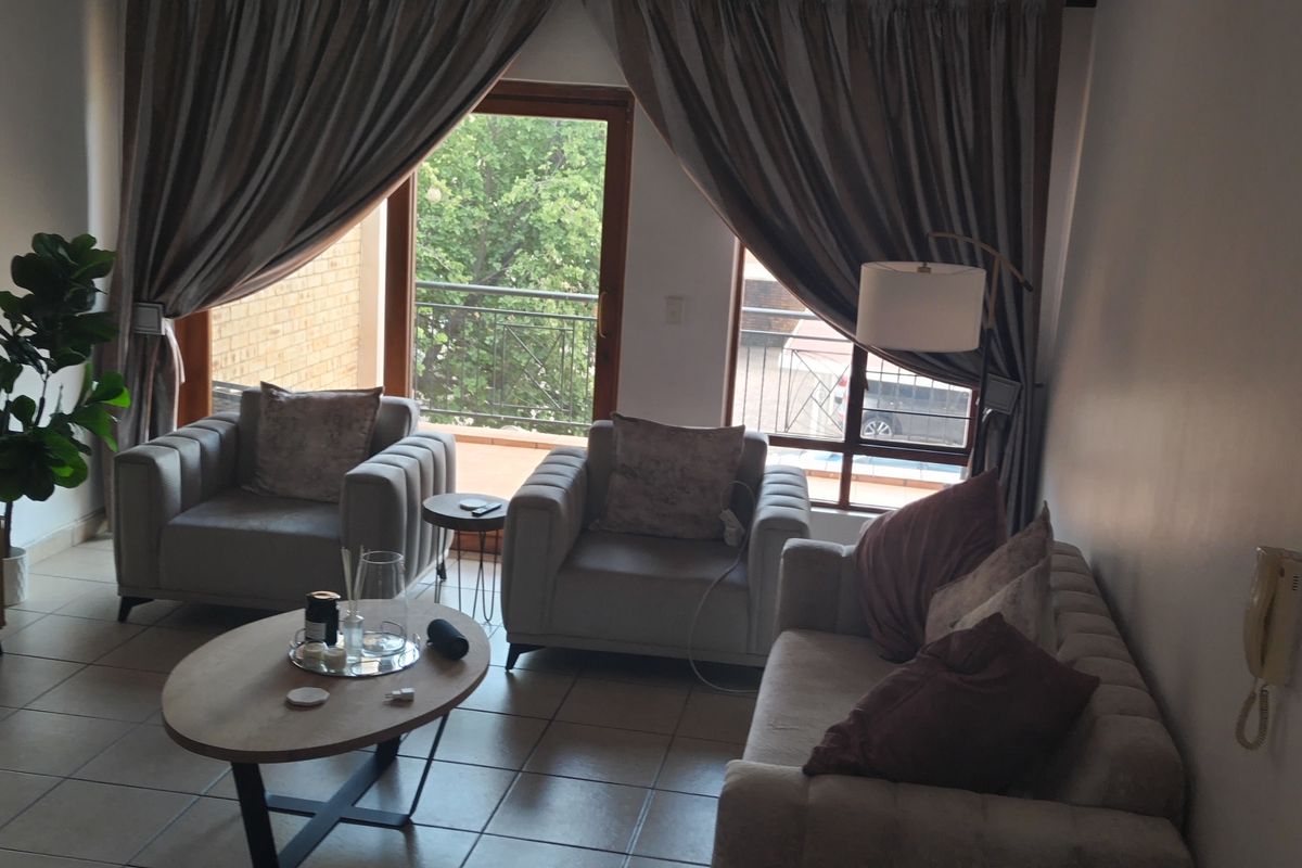 A comfortable living room featuring tiled flooring and a sliding glass door that provides access to a private balcony.