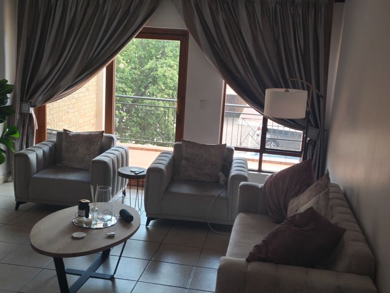 A comfortable living room featuring tiled flooring and a sliding glass door that provides access to a private balcony.