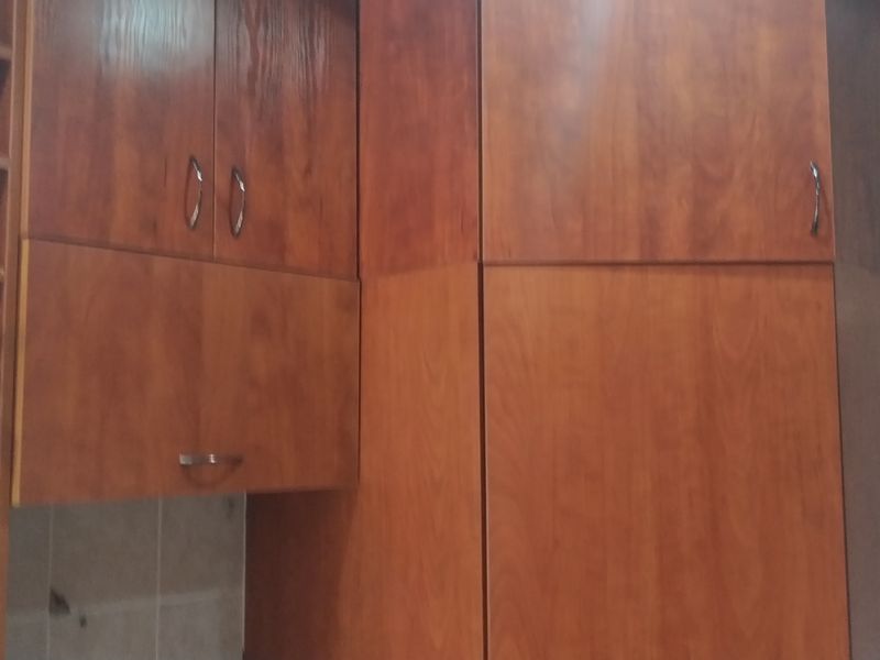 A kitchen area featuring built-in wooden cabinetry with integrated wine storage and tiled wall finishes.