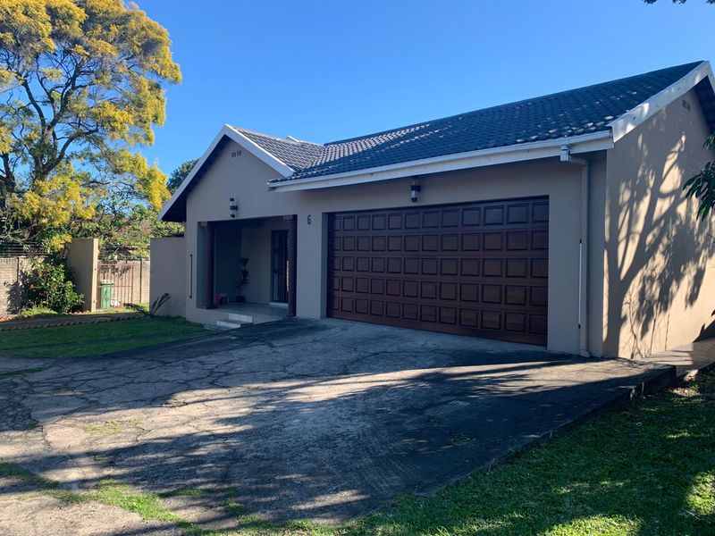Front elevation of a single-story house featuring a tiled roof, covered entrance, and a double garage with a concrete driveway.