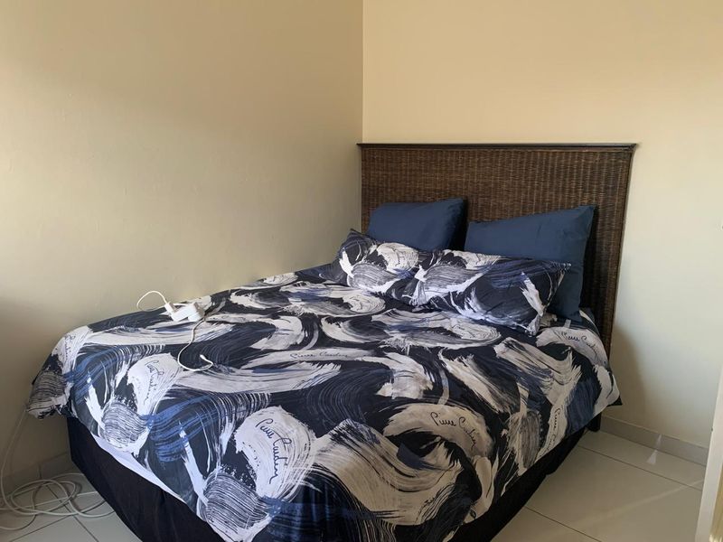 A simple bedroom featuring neutral wall finishes and tiled flooring, providing a functional and clean space.