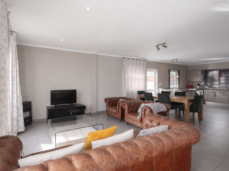 Spacious open-plan living and dining area featuring tiled floors, recessed lighting, and a modern kitchen with ample cabinetry and integrated appliances.
