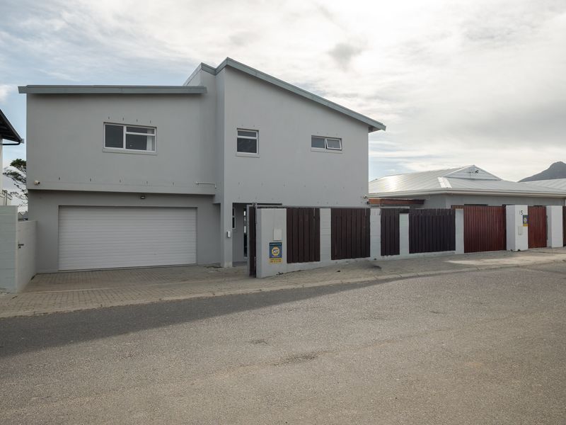 Front exterior view of a modern two-story house featuring a garage, paved driveway, and secure boundary wall with timber fencing.