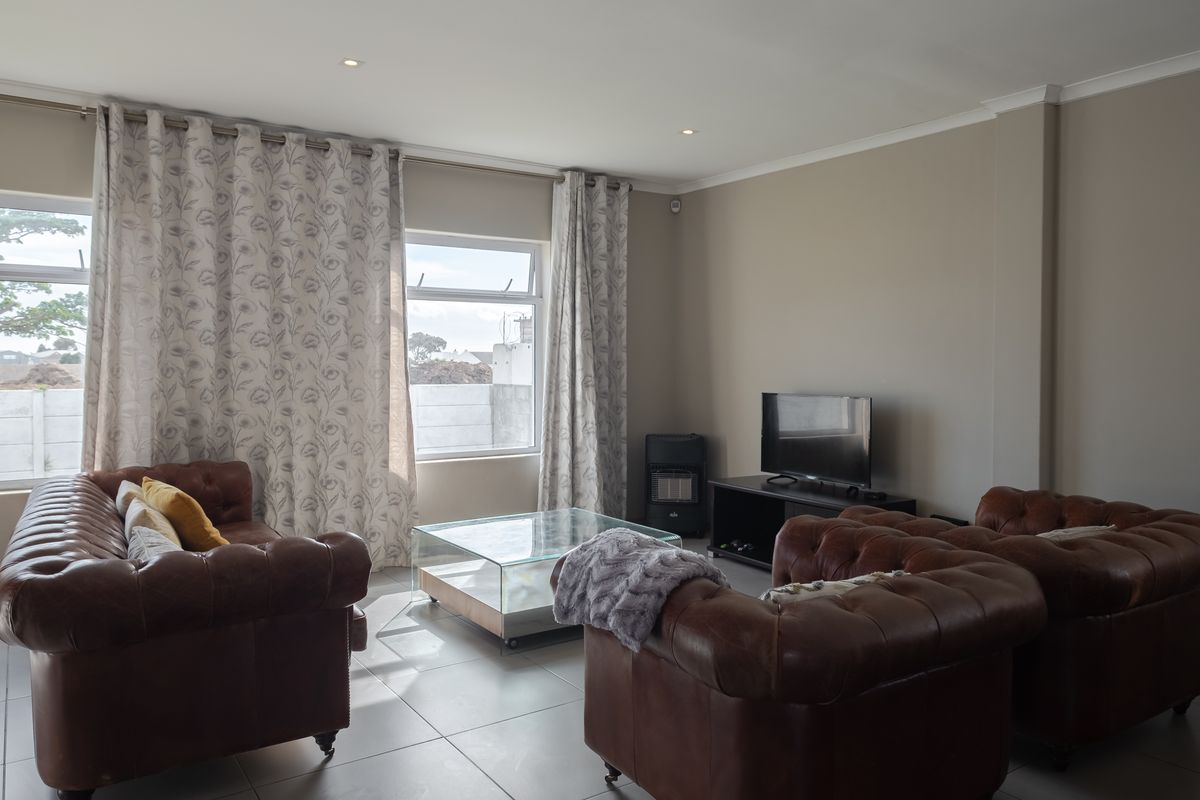 A well-lit living room featuring neutral tiled flooring, recessed downlights, and a built-in gas heater, offering a comfortable and functional space.