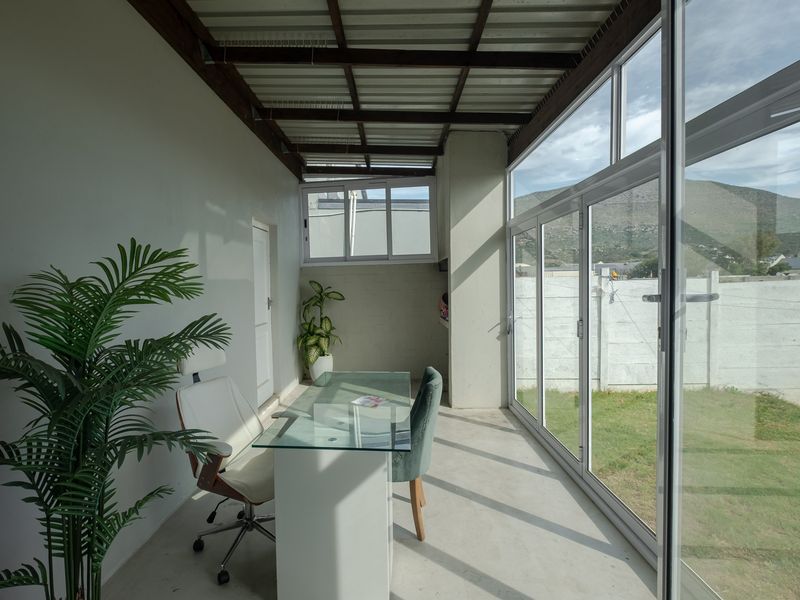 Enclosed patio area featuring exposed beam ceiling, concrete flooring, and large sliding glass doors providing access to the rear garden and mountain views.
