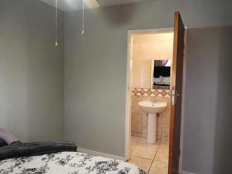 Bedroom featuring a neutral color palette and an en-suite bathroom with a pedestal basin and tiled finishes.
