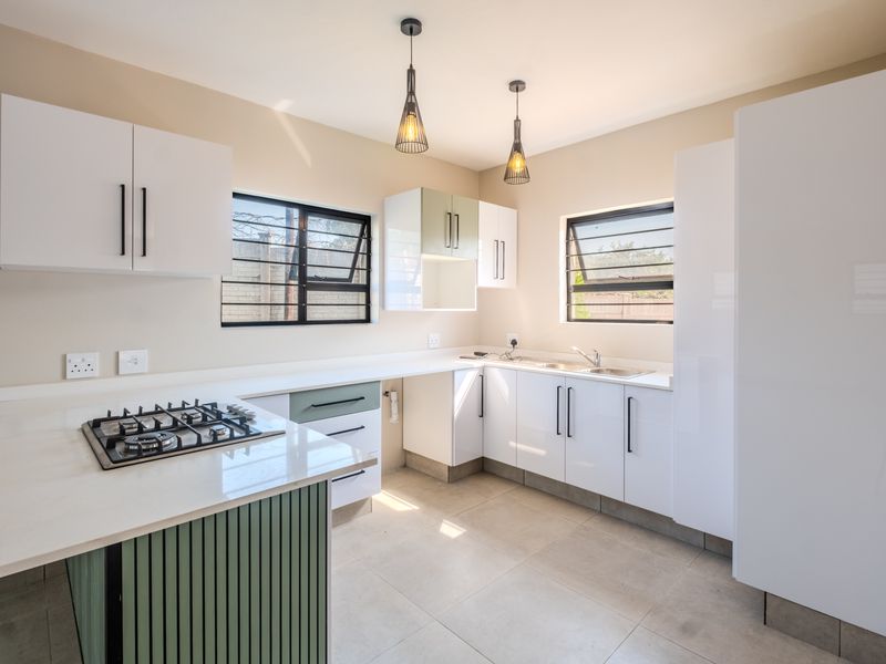 Modern kitchen featuring white cabinetry, quartz countertops, a gas hob, and tiled flooring, offering a clean and functional workspace.