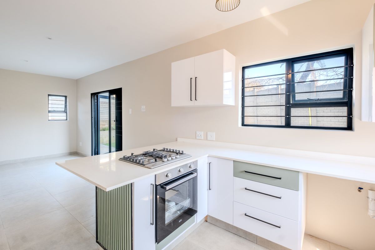 Modern kitchen featuring white cabinetry, stone countertops, a built-in gas hob and oven, with direct access to the outdoor area.