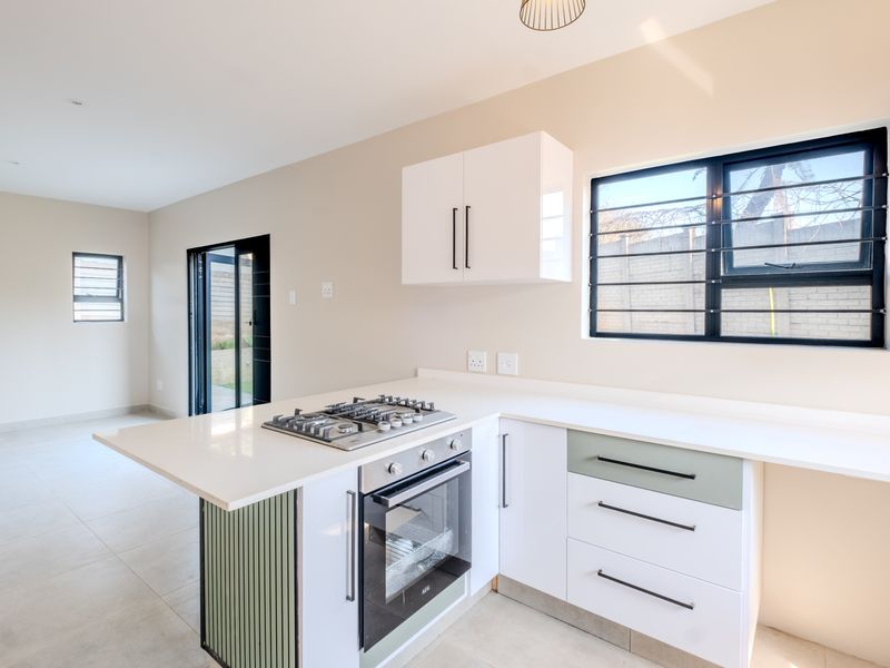 Modern kitchen featuring white cabinetry, stone countertops, a built-in gas hob and oven, with direct access to the outdoor area.