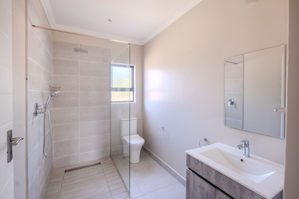 Modern bathroom featuring a spacious walk-in shower with glass screen, contemporary vanity with basin, and neutral tiling throughout.