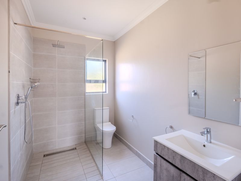 Modern bathroom featuring a spacious walk-in shower with glass screen, contemporary vanity with basin, and neutral tiling throughout.