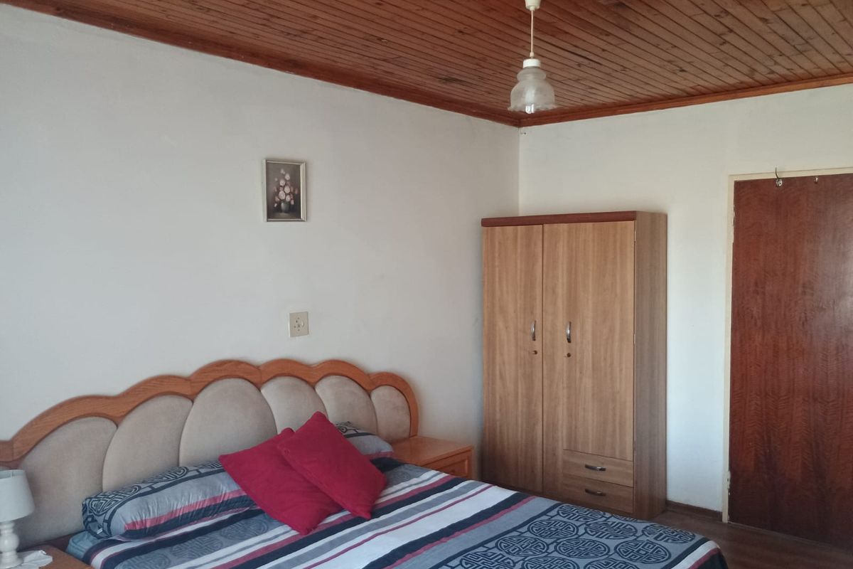 A bedroom featuring a classic timber-clad ceiling and a solid wooden door, offering a traditional aesthetic with potential for modern updates.
