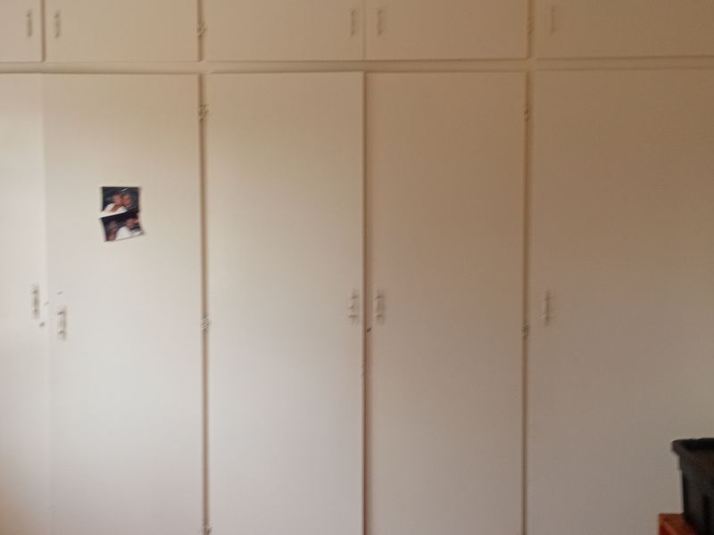 A bedroom featuring extensive floor-to-ceiling built-in cupboards with integrated overhead storage compartments.