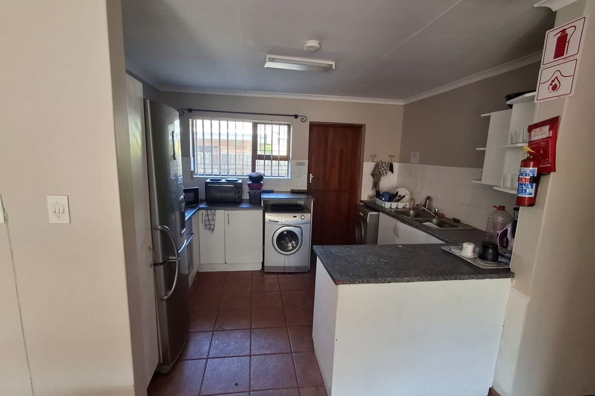 Functional kitchen featuring tiled flooring, built-in cabinetry, laminate countertops, and a double sink, with security bars on the window for added safety.