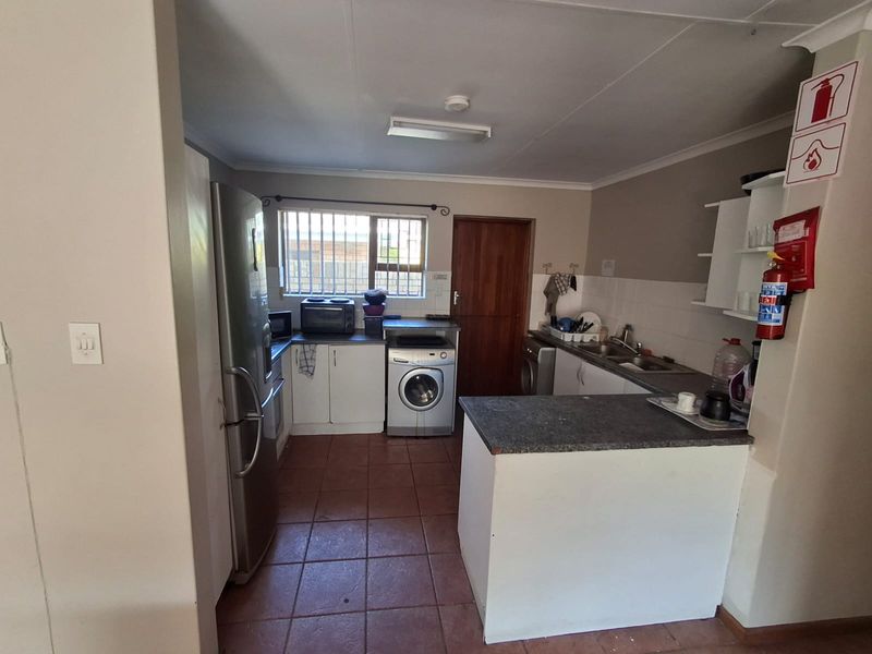 Functional kitchen featuring tiled flooring, built-in cabinetry, laminate countertops, and a double sink, with security bars on the window for added safety.